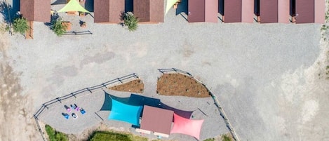 Vista aérea de un hotel con varias habitaciones, un estacionamiento y un área exterior cercada con asientos.