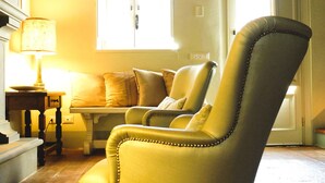 A room with a high ceiling, exposed wooden beams, a window with a view, a sofa, and a lamp. - "Casa il Noce" in the hills of Lucca with swimming pool 30 min from the sea of Viareggio (Pescaglia)