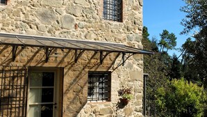 A stone building with a door, a window with bars, and a welcome mat. - "Casa il Noce" in the hills of Lucca with swimming pool 30 min from the sea of Viareggio (Pescaglia)