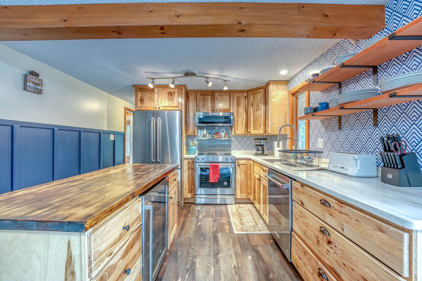 A kitchen with wooden cabinets, stainless steel appliances, and a blue wall.