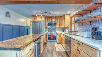 A kitchen with wooden cabinets, stainless steel appliances, and a blue wall.