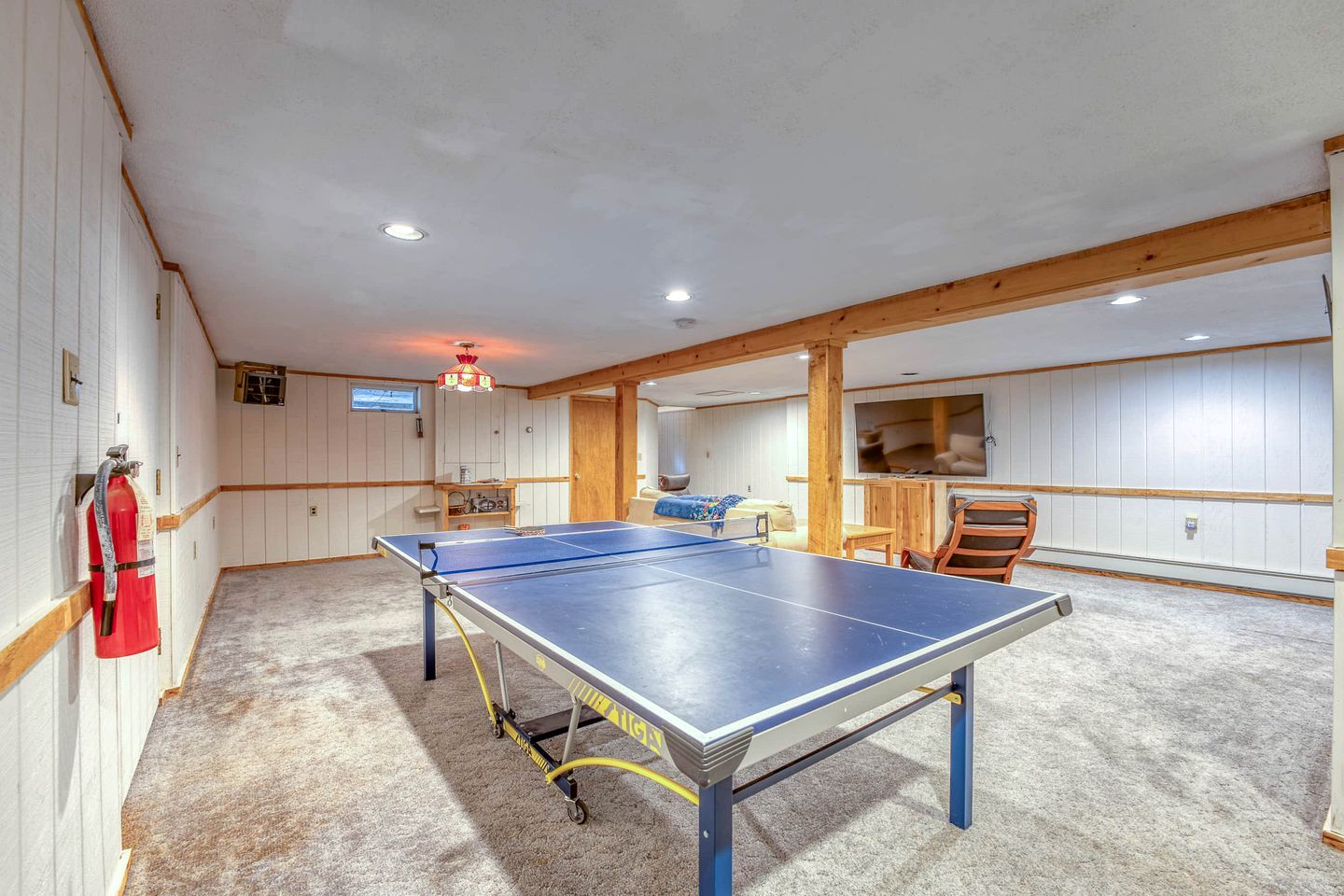 Une pièce équipée d’une table de ping-pong, d’un extincteur et d’un téléviseur.
