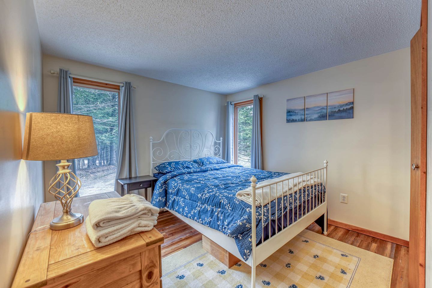 Une chambre à coucher avec un lit, une table de chevet, une lampe et des fenêtres.