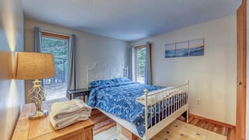 Une chambre à coucher avec un lit, une table de chevet, une lampe et des fenêtres.
