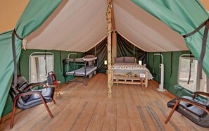 Una habitación con carpas, literas, un escritorio, una silla y una cama.