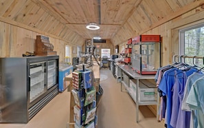 A cabin interior with a kitchen area, a refrigerator, a dining table, and a clothing rack. - Safari Tent Bliss for You and Your Best Friend: Pet-Friendly Glamping in Suches, Georgia (Suches)