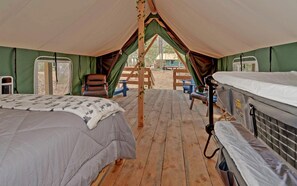 Una carpa con dos camas, una terraza de madera y vistas al exterior.