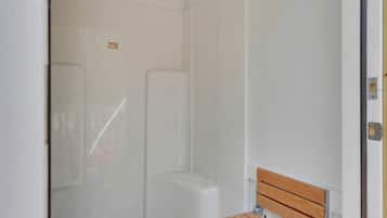 Ein Badezimmer mit Dusche, Toilette und Sitzbank.