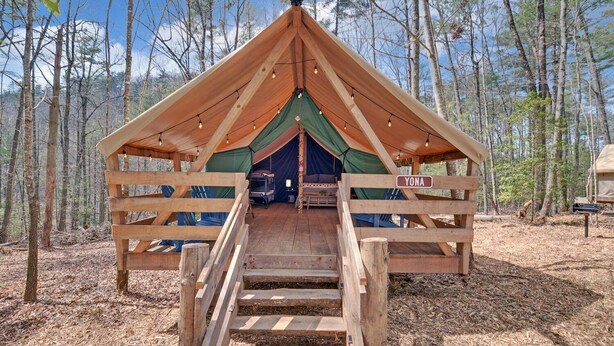 Una cabaña de madera con una rampa que lleva a una entrada cubierta, rodeada de árboles.