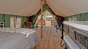 Una carpa con dos camas, una terraza de madera y vistas al exterior.