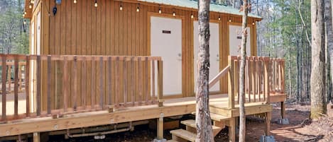 Une cabane en bois avec une véranda, une porte et une petite fenêtre.