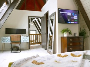 A bedroom with a bed, a TV mounted on the wall, a dresser, and a mirror. - Luxury A-Frame with Hot Tub for Dreamy Vacations in Colorado (Blue River)