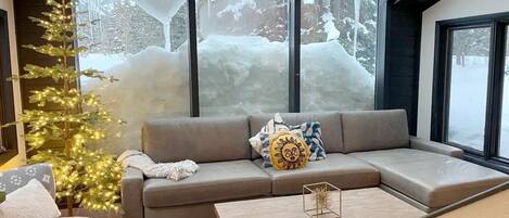 A modern living room with a sectional sofa, a coffee table, and a Christmas tree.