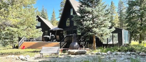 A lodge with a wooden deck, a staircase, and a small cabin-like structure.