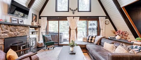 Ein gemütliches Wohnzimmer im Loft-Stil mit Kamin aus Stein, einem großen Fenster und einer komfortablen Sitzecke.