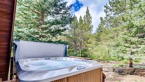 Ein Whirlpool auf einer Holzterrasse mit Wald im Hintergrund.