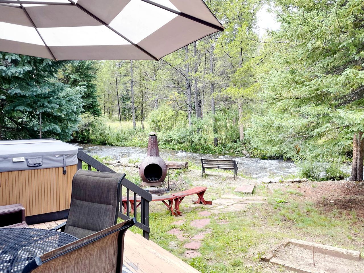 Une terrasse dotée de mobilier d’extérieur, d’un jacuzzi, d’un foyer et offrant une vue sur une rivière.