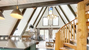 Ein Loft-Zimmer mit Küchenbereich, einer Holztreppe und Blick ins Freie.
