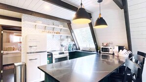 Eine moderne Küche mit Kochinsel, Edelstahlgeräten und Pendelleuchten.