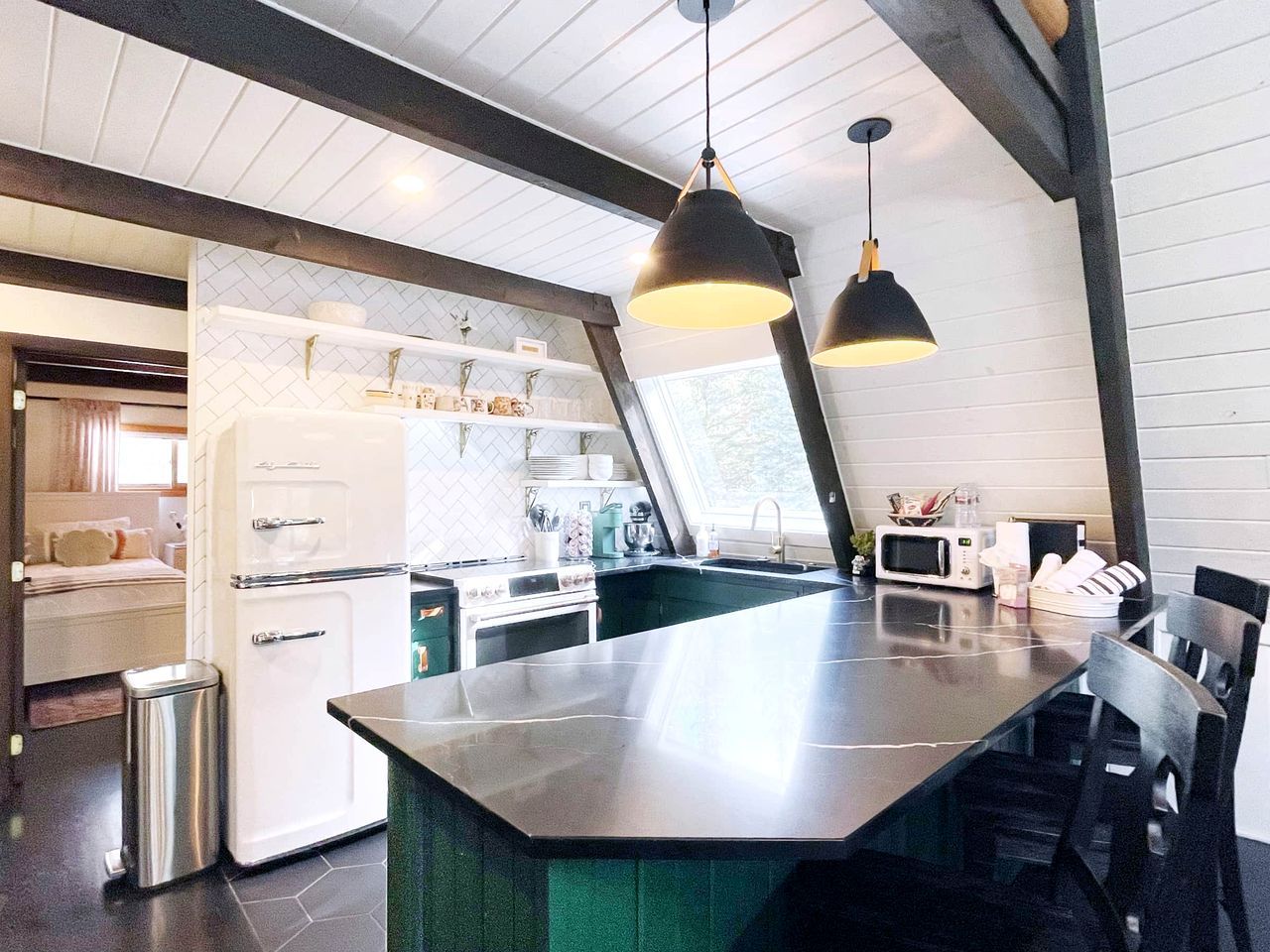 Une cuisine moderne dotée d’un îlot central, d’appareils électroménagers en acier inoxydable et de luminaires suspendus.