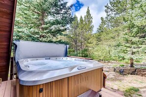 A hot tub on a wooden deck with a forest backdrop. - Luxury A-Frame with Hot Tub for Dreamy Vacations in Colorado (Blue River)