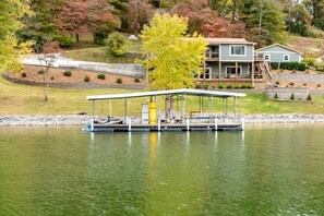A house with a dock extending into a lake, surrounded by trees and a grassy area. - Lynchburg's Best-Kept Secret: A Unique Rental with Private Dock and Open Water Views (Lynchburg)