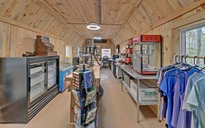 A cabin interior with a kitchen area, a refrigerator, a dining table, and a clothing rack. - Ultimate Glamping Adventure in Suches, Georgia with a Safari Tent Retreat (Suches)