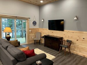 Un salon chaleureux avec un canapé, des fauteuils, un téléviseur et un mur en bois.