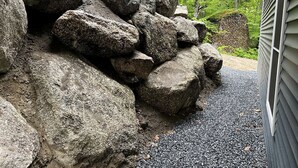 Una strada sterrata conduce a una casa con un ammasso di grosse rocce.