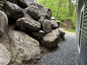 Une allée de gravier mène à une maison devant laquelle se trouve un tas de gros rochers.