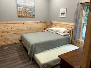 Une chambre à coucher avec un lit, une table de chevet, une lampe et une fenêtre avec des rideaux.