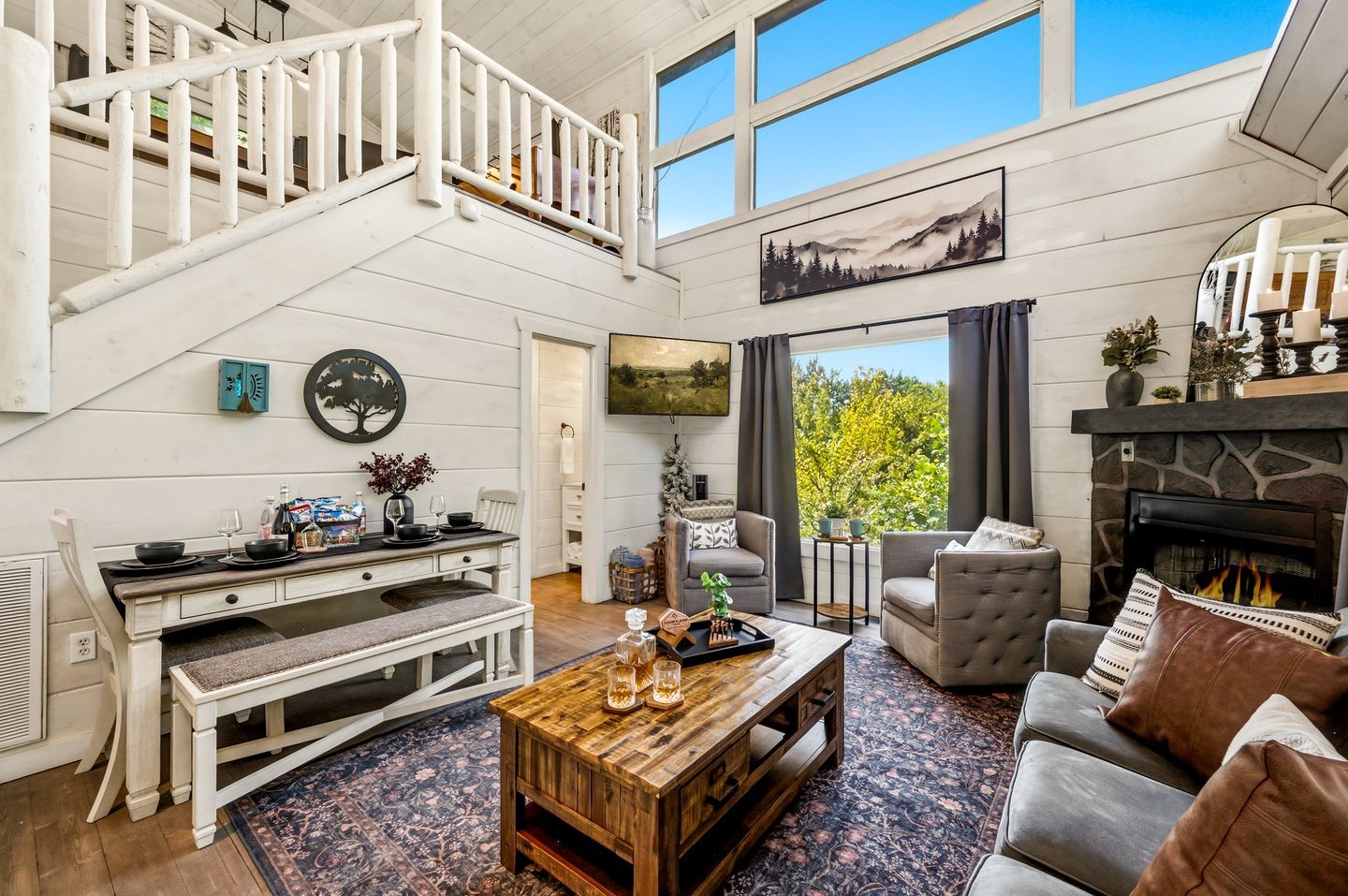 A spacious living room with a fireplace, a dining area, and a staircase leading to an upper level.