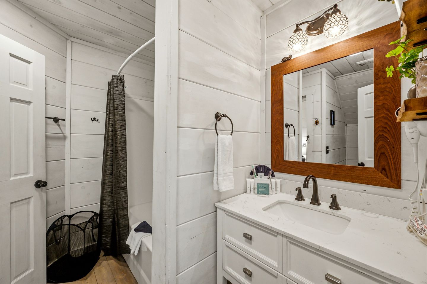 A bathroom with a white vanity, a large mirror, and a shower with a curtain.