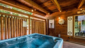 Une cabane en bois dotée d’un bain à remous, de murs en bois et d’une fenêtre donnant sur l’extérieur.