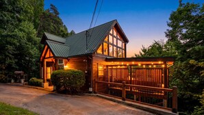 Une cabane dotée d’un toit en pente, de grandes fenêtres et d’une terrasse en bois.