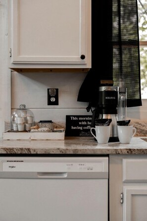 A kitchen counter with a coffee maker, cups, and a sign. - Gorgeous Secluded Wooden Cabin with Hot-tub and Pool Table in Sevierville, Tennessee (Sevierville)