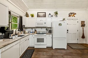 A kitchen with white cabinets, a microwave, a refrigerator, and a stove. - Gorgeous Secluded Wooden Cabin with Hot-tub and Pool Table in Sevierville, Tennessee (Sevierville)