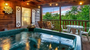 Une terrasse en bois avec un jacuzzi, des sièges d’extérieur et une vue sur les arbres.