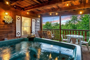 A wooden deck with a hot tub, outdoor seating, and a view of trees. - Gorgeous Secluded Wooden Cabin with Hot-tub and Pool Table in Sevierville, Tennessee (Sevierville)