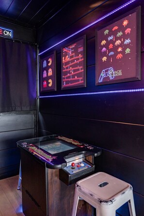 A retro arcade with neon signs, a classic arcade machine, and a small stool. - Gorgeous Secluded Wooden Cabin with Hot-tub and Pool Table in Sevierville, Tennessee (Sevierville)