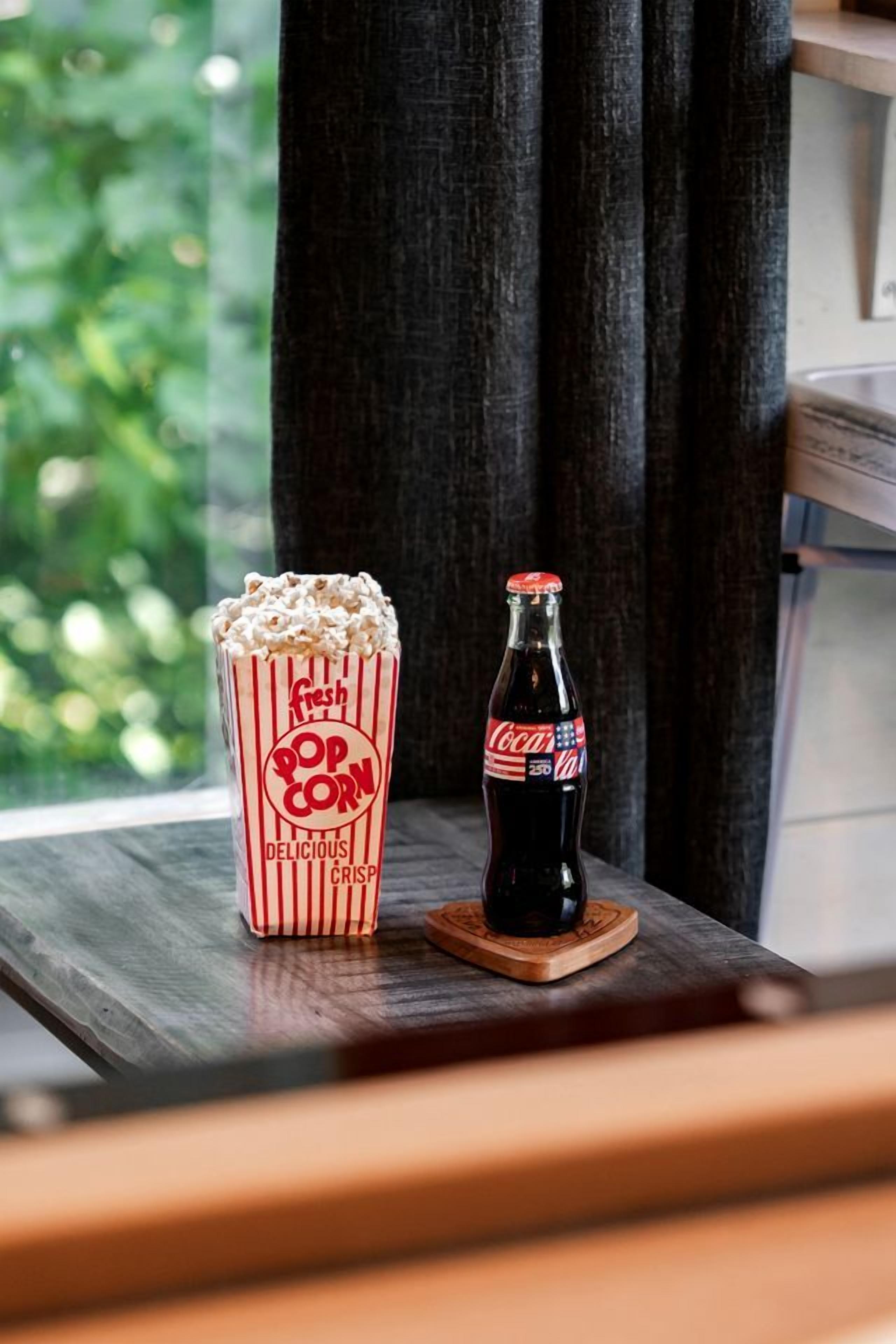 Une table en bois avec une bouteille de Coca-Cola et un récipient rempli de pop-corn.