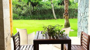 Eine Terrasse im Freien mit einem Holztisch und -stühlen, einer Steinmauer und Blick auf einen üppigen Garten.