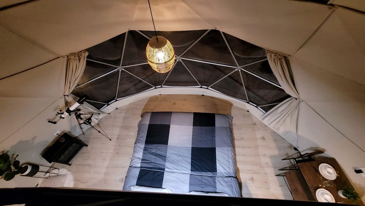 A tent with a checkered floor, a hanging light fixture, and a table with plates.