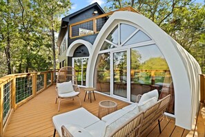 A modern house with a deck, large windows, and outdoor furniture.