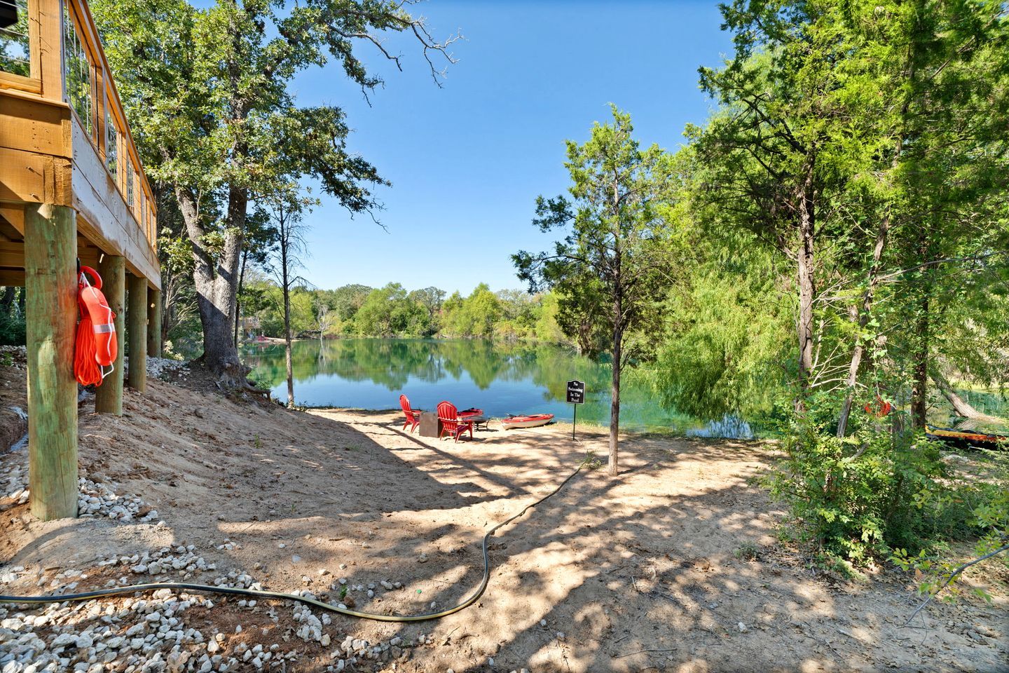 A lakeside cabin with a dock, red chairs, and a sign indicating a picnic area.