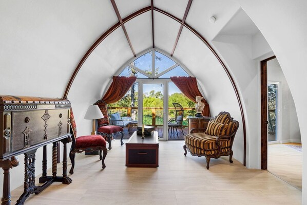 Une pièce dotée d’un plafond voûté, d’une table en bois, d’un canapé et d’une chaise.