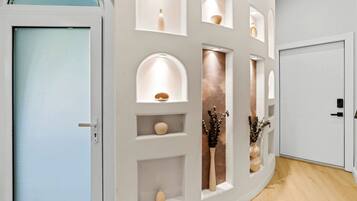 A hallway with a white door, a white wall with built-in shelves, and a wooden floor.