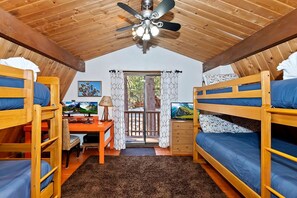 A compact room with bunk beds, a desk with a computer, a ceiling fan, and a view through a door. - Cute Cabin with Fireplace and Private Patio in Big Bear Lake, California (Big Bear Lake)
