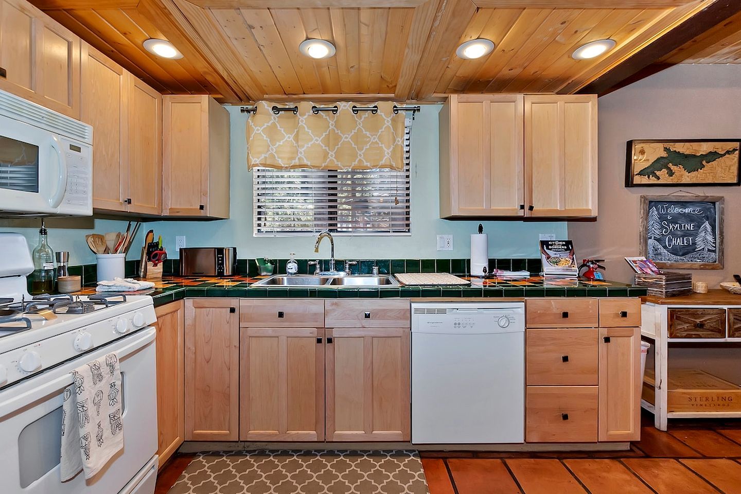A kitchen with wooden cabinets, a stove, a dishwasher, and a window with blinds.