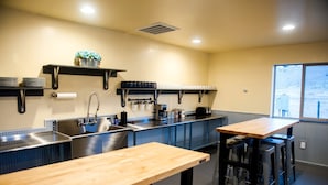 A kitchen with a sink, stove, and wooden table. - Gorgeous A-Frame Cabin for Two near Yellowstone with Incredible Glampground Amenities in Emigrant, Montana (Emigrant)